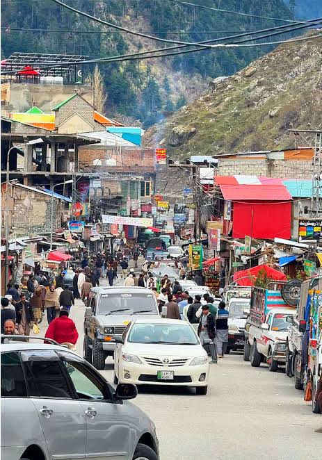 Busy main street of Kalam Bazaar with shops, jeeps and food stalls
