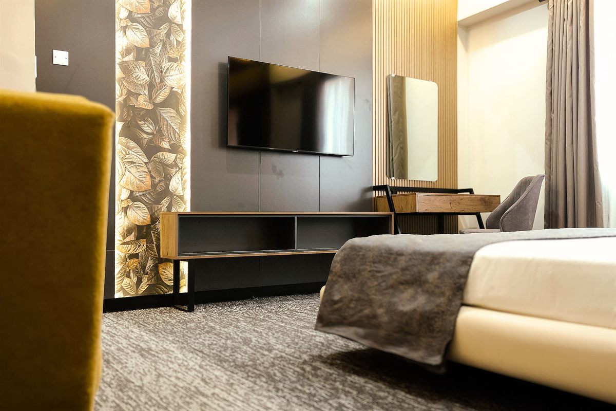 King room with wall-mounted TV, dressing desk and soft lighting at LEORK Hotels Rawalpindi, set up for a long stay.