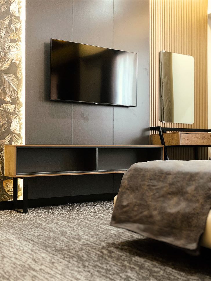 King room with wall-mounted TV, dressing desk and soft lighting at LEORK Hotels Rawalpindi, set up for a long stay.