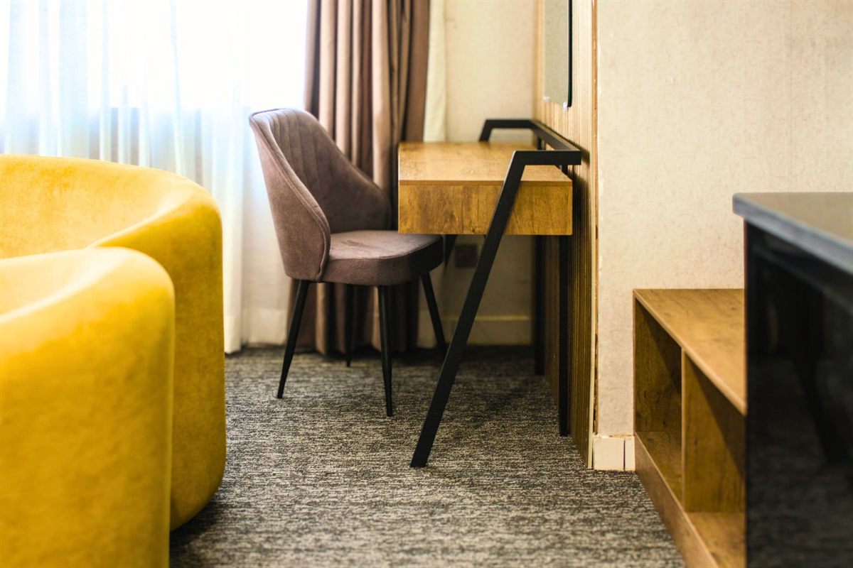 Wooden work desk and upholstered chair by the window in a Deluxe King room at LEORK Hotels Rawalpindi