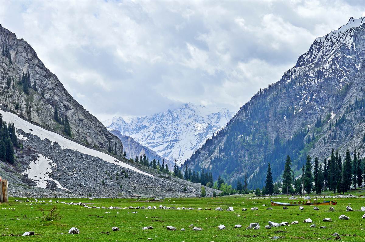 The upper valley opening out near Kalam with green meadows below snow-covered mountains