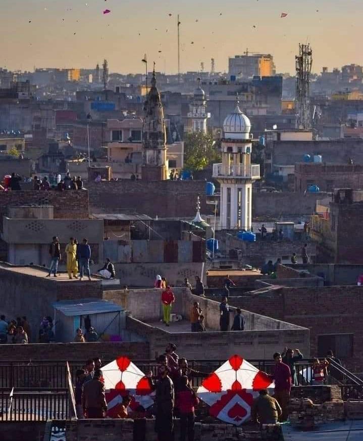 Kites flying over the rooftops and minarets of Rawalpindi's old city at sunset
