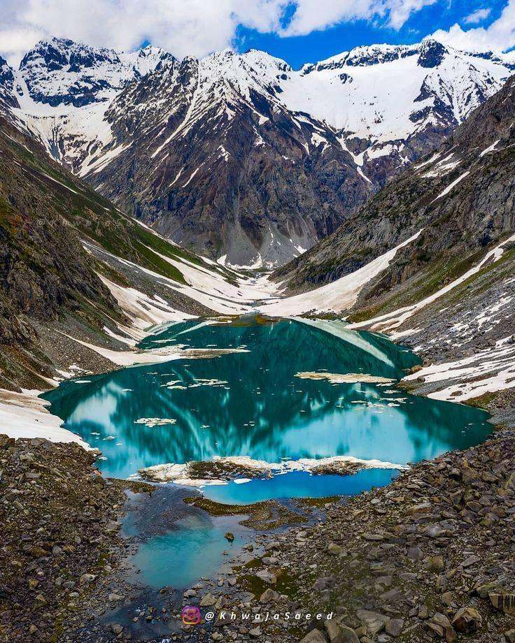 Alpine lake above Utror with snow still on the surrounding slopes in early summer