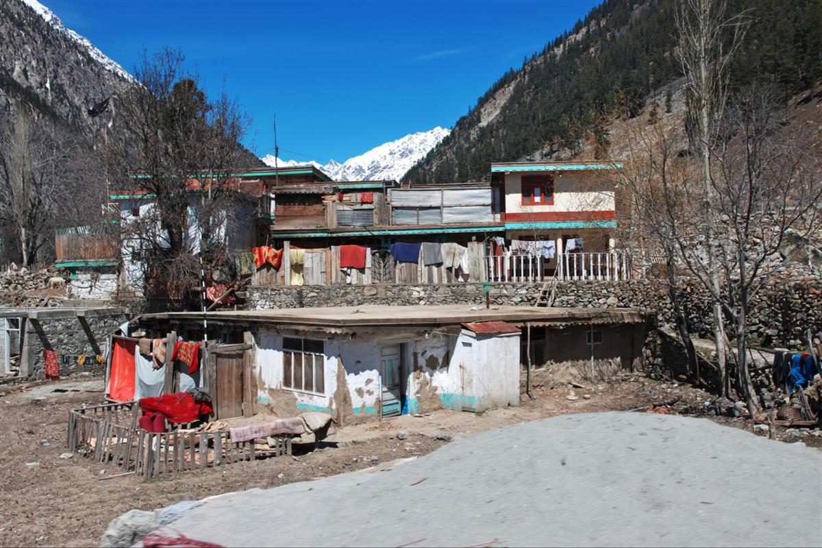Traditional stone and timber houses of a Swat valley village with snow peaks behind