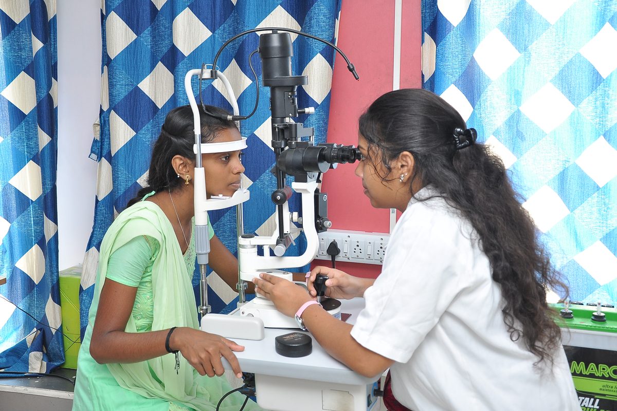 An eye-care specialist examining a patient with a slit lamp in a clinic.
