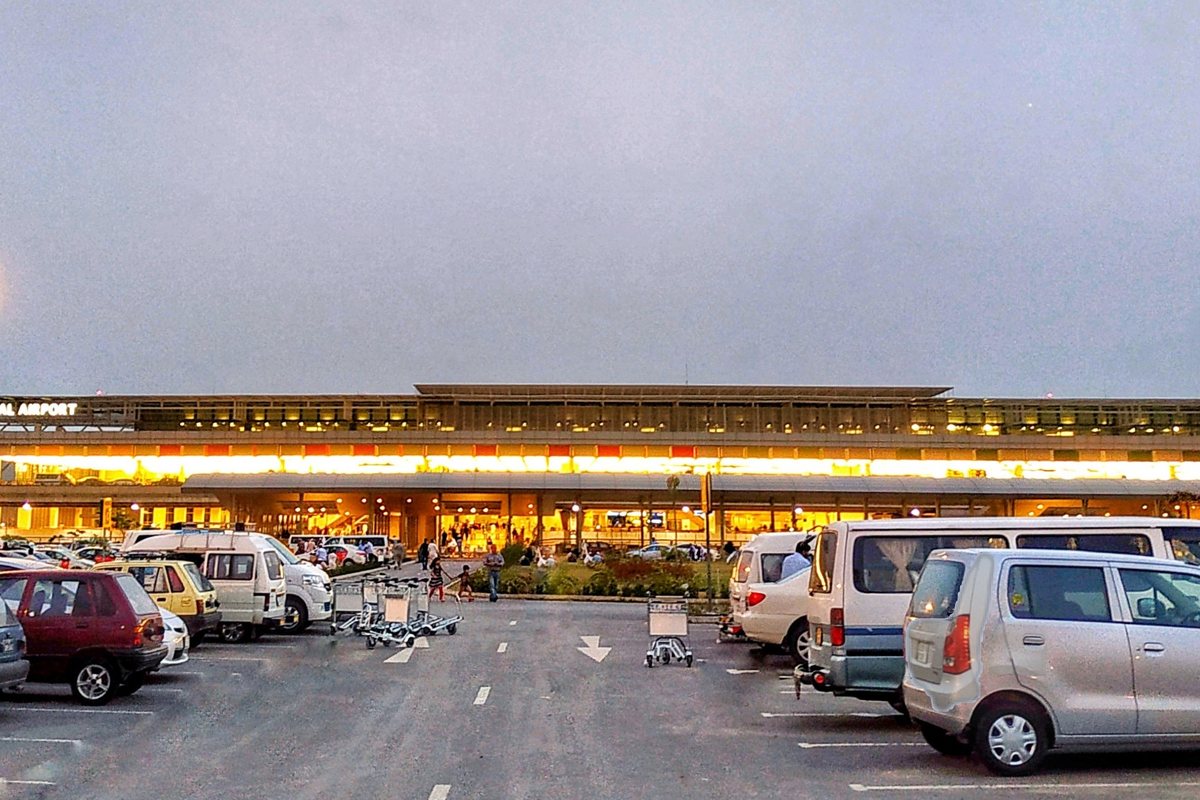 Islamabad International Airport terminal at dusk with the car park in front.