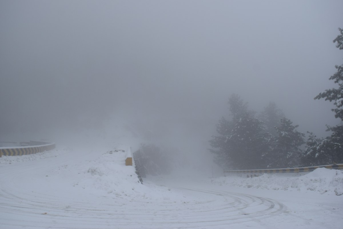 A snowy hairpin road in thick fog near Nathia Gali