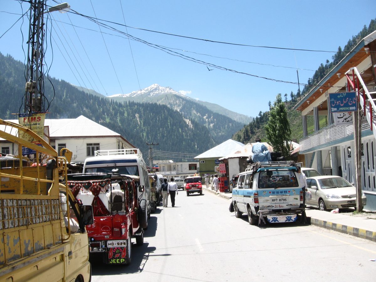 Naran bazaar with jeeps and forested slopes behind the town