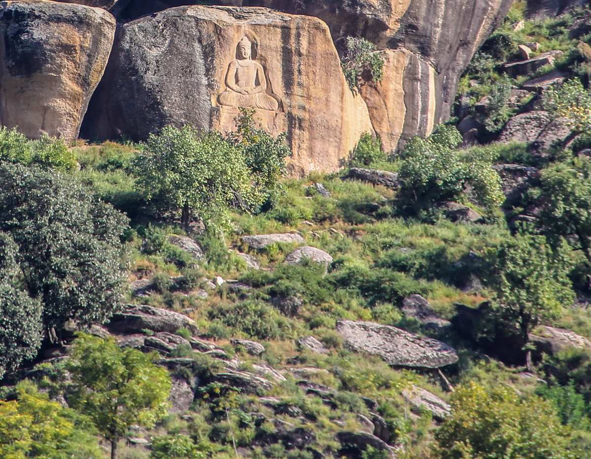 The restored Jahanabad Buddha carved into a rock face above a green hillside