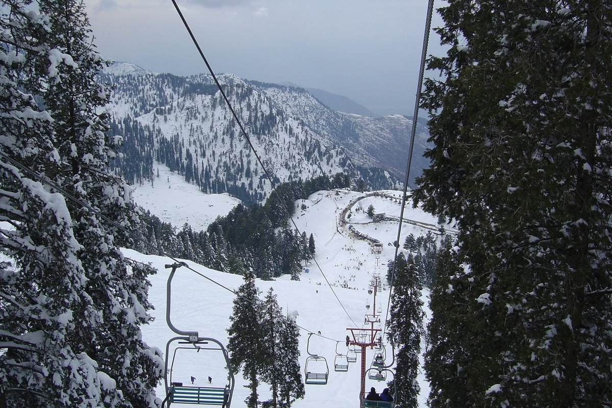View from the chairlift at Malam Jabba down through snow-covered pines to a busy ski slope.