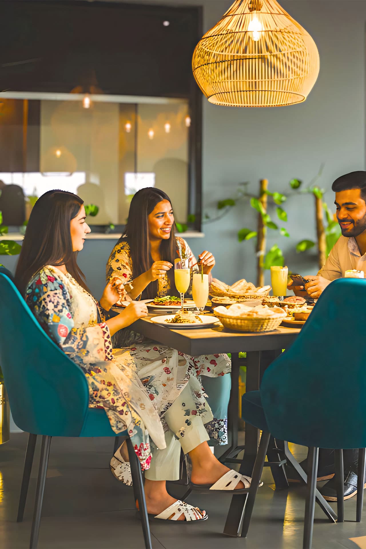Little Tree Café mobile view with guests enjoying cocktails and burgers, fancy lighting, plants, chairs, table, and lively atmosphere at LEORK Hotels Rawalpindi Islamabad