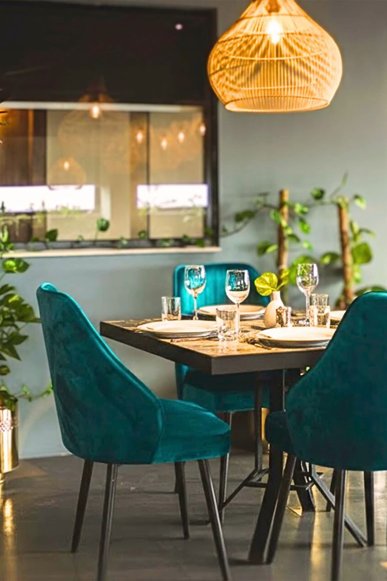 Little Tree Café mobile terrace view with four teal chairs, chic decor, set table, plants, and inviting atmosphere at LEORK Hotels Rawalpindi Islamabad