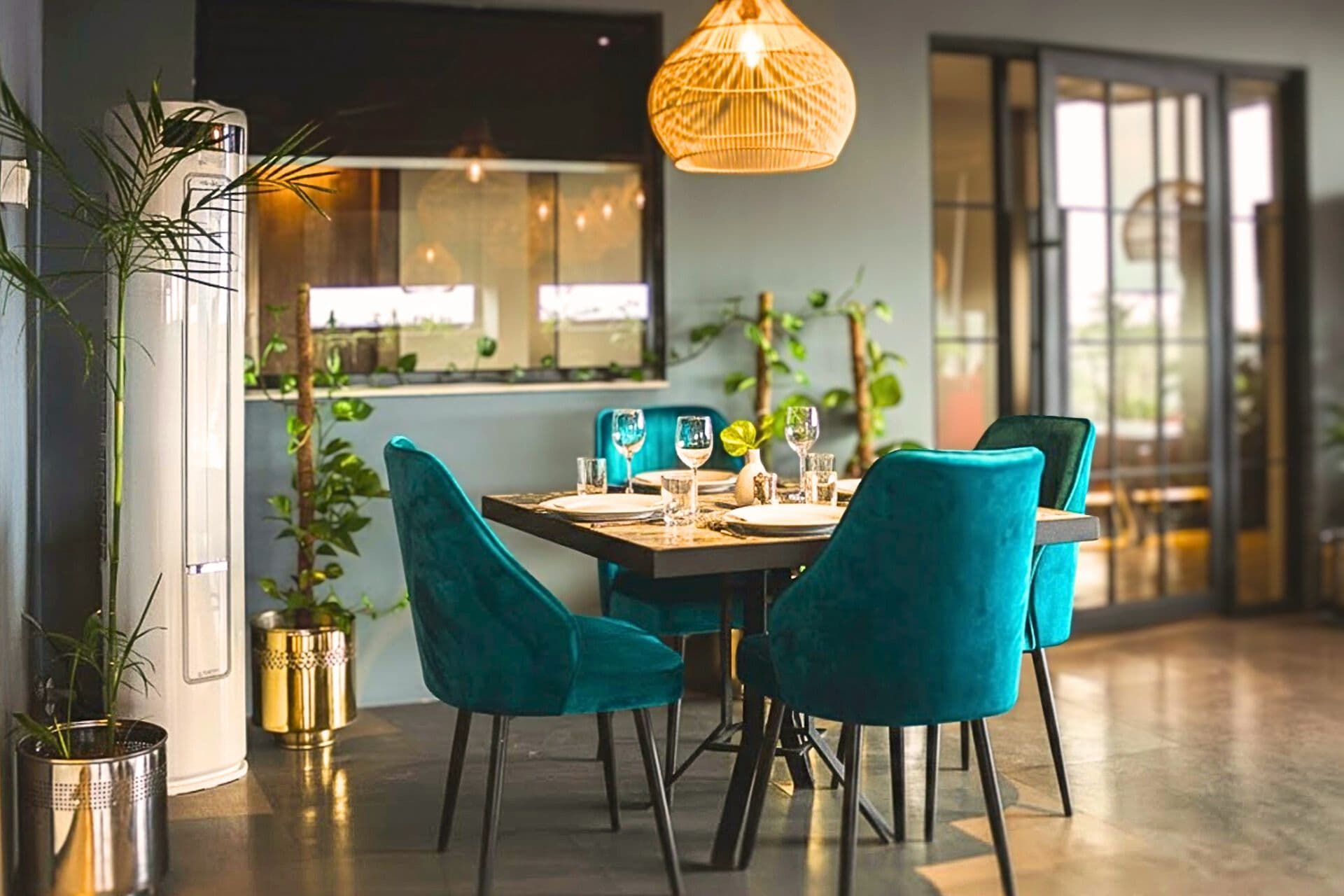 Little Tree Café terrace view with four teal chairs, chic decor, set table, plants, warm lighting, and vibrant atmosphere with large windows at LEORK Hotels Rawalpindi Islamabad