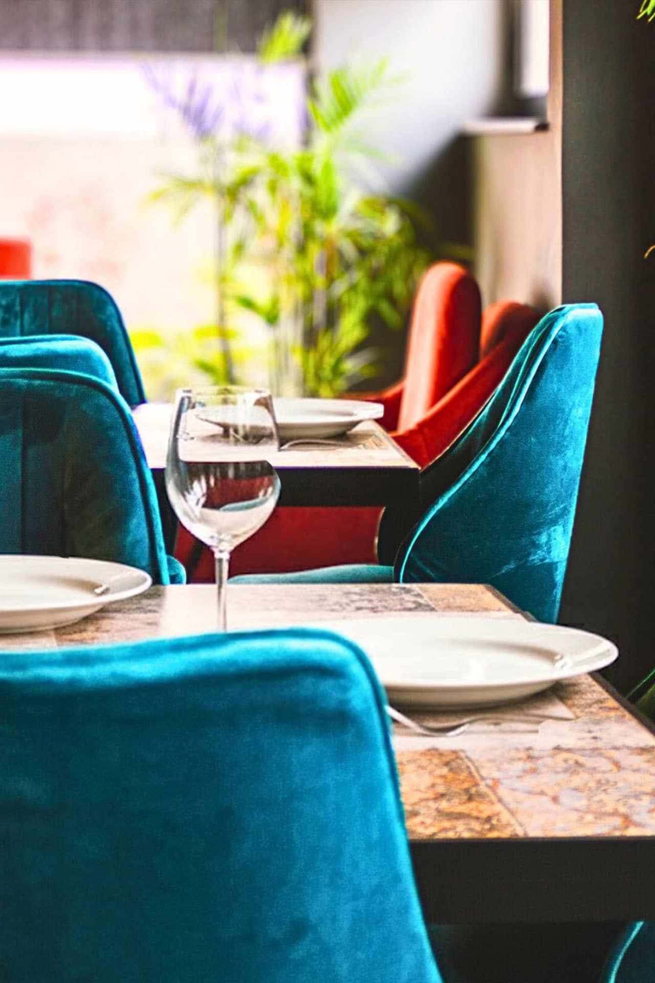 Little Tree Café mobile close-up of teal chairs, plants, chair details, and inviting ambiance at LEORK Hotels Rawalpindi Islamabad