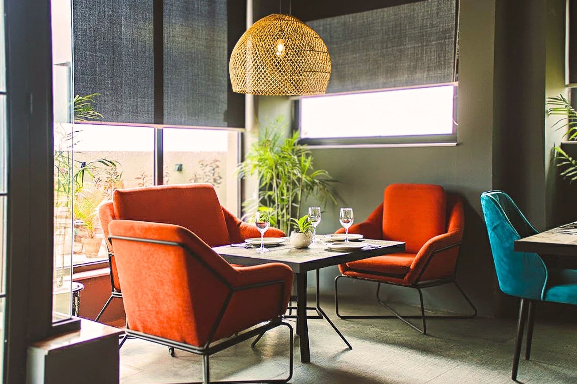 Little Tree Café with red chairs, exclusive coffee table, plants, outside view, warm ambience, and large windows at LEORK Hotels Rawalpindi Islamabad