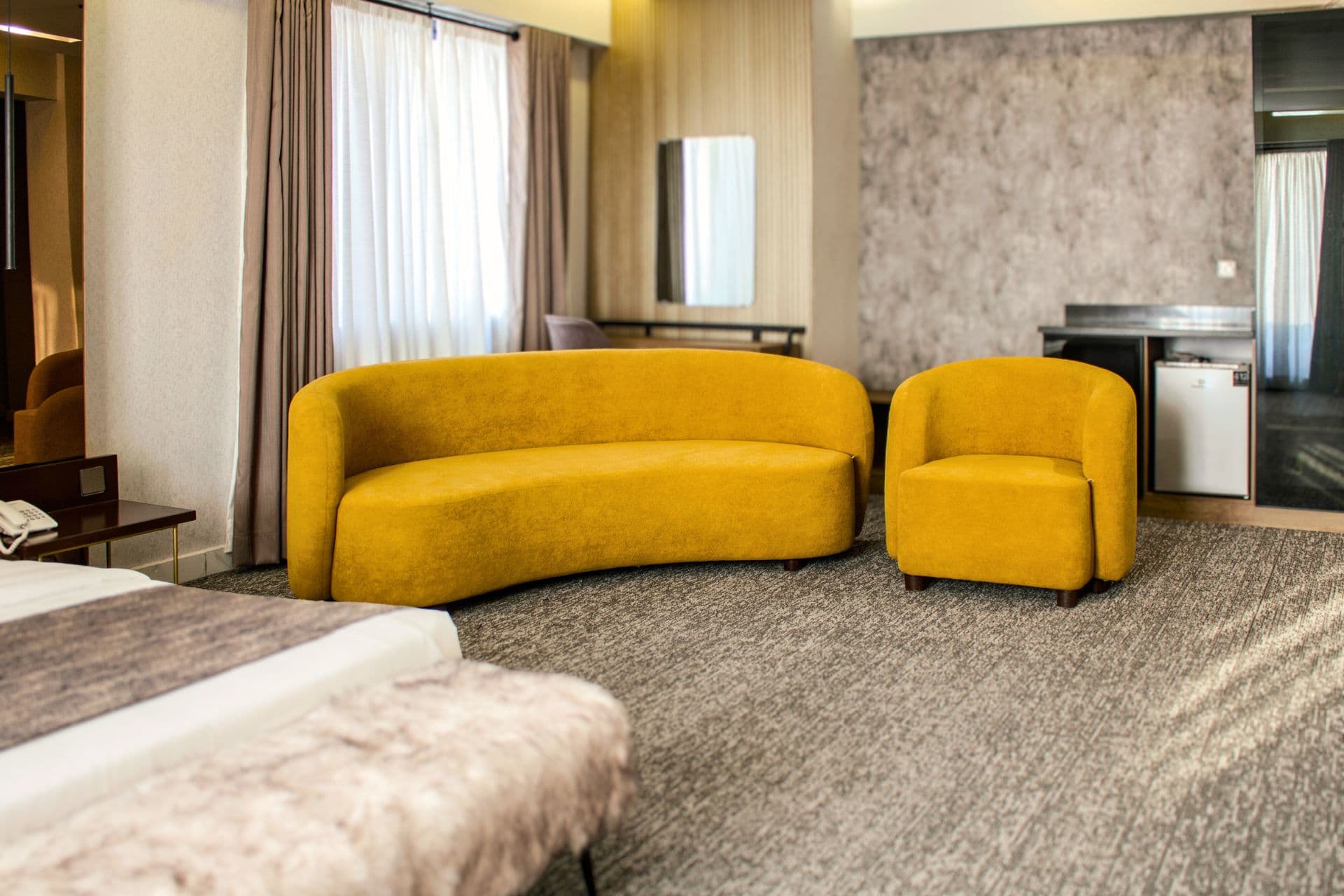 Deluxe King Room full view with modern three-seater sofa, single sofa, study desk, bed, fridge, wardrobe, window, and curtains at LEORK Hotels Rawalpindi Islamabad