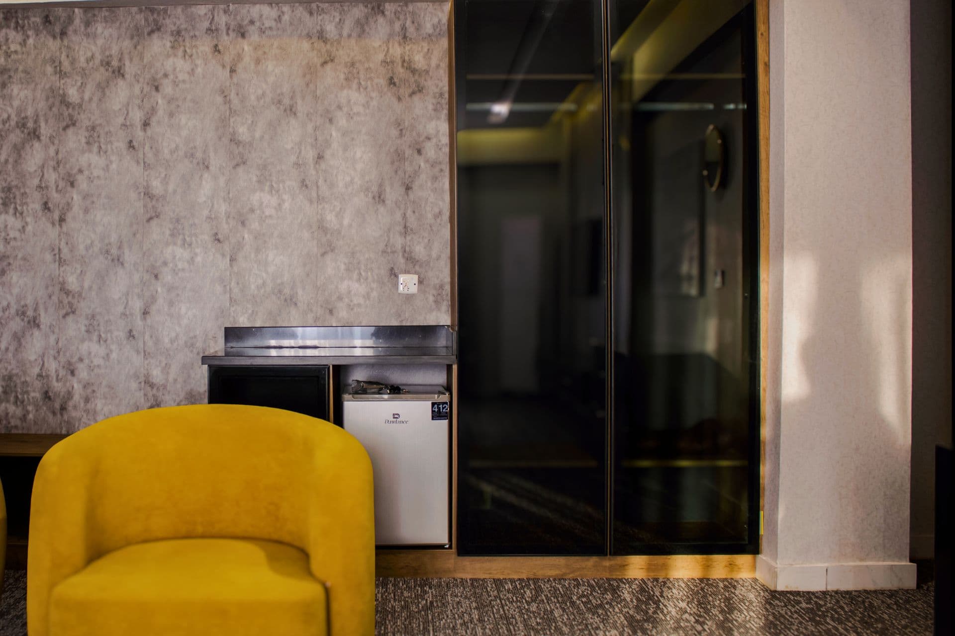 Deluxe King Room with single sofa, wardrobe, and fridge at LEORK Hotels Rawalpindi Islamabad