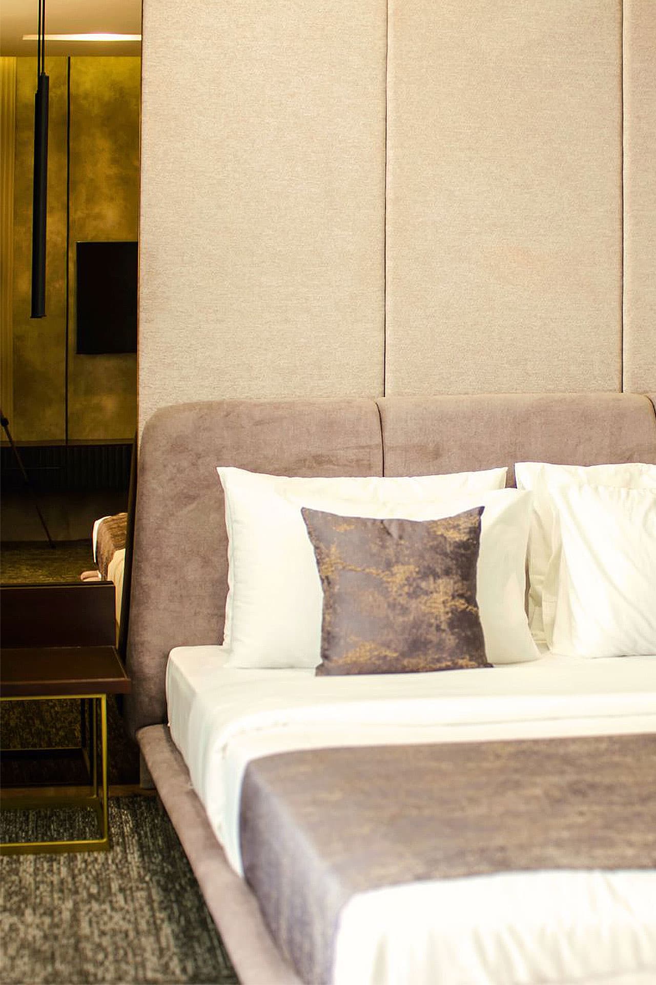 Deluxe King Room interior with bed, sofa, side table, phone, headboard, and mirrors at LEORK Hotels Rawalpindi Islamabad