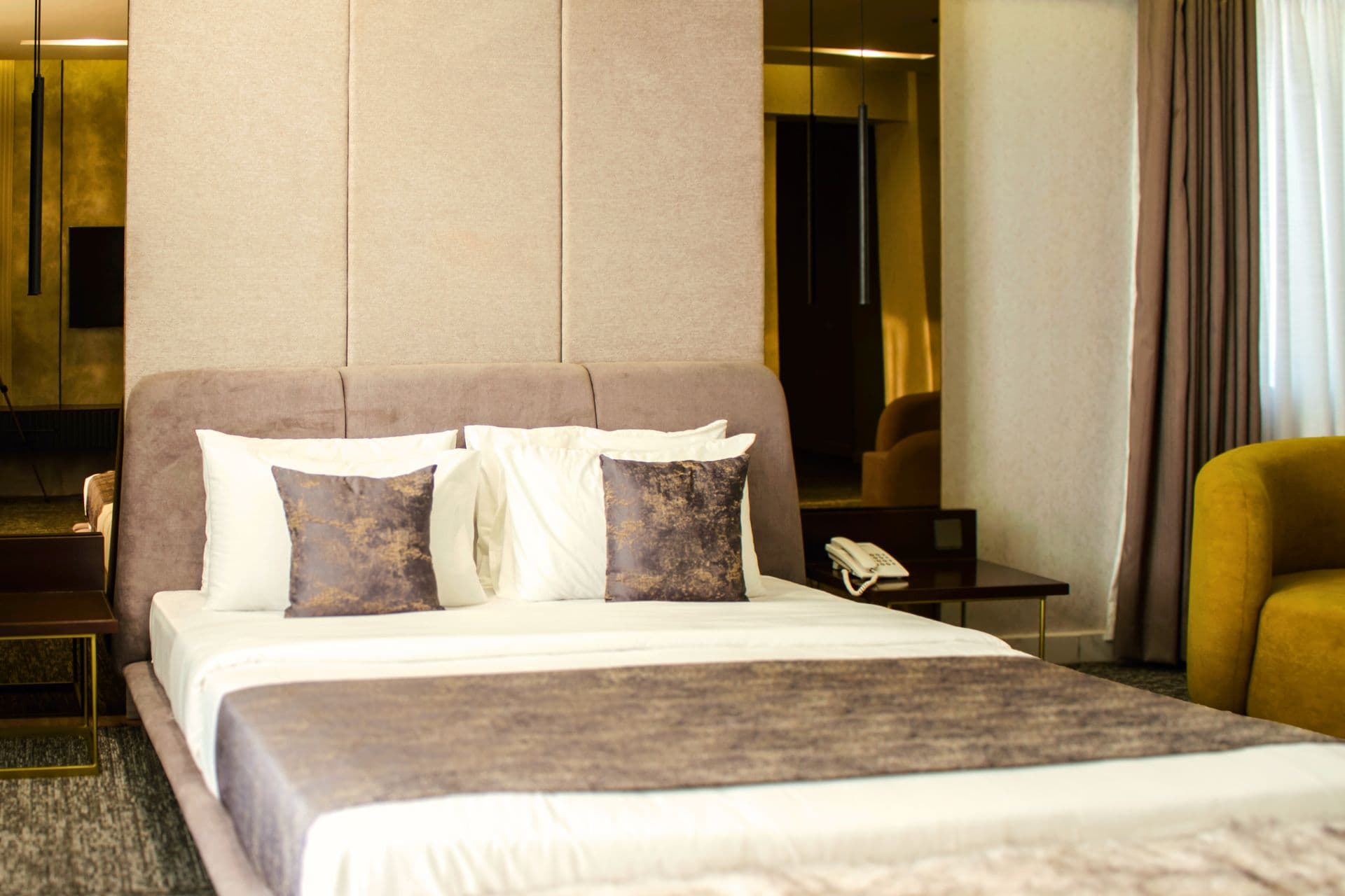 Deluxe King Room interior showing bed, sofa, side table, phone, headboard, mirrors, carpet, and window curtains at LEORK Hotels Rawalpindi Islamabad