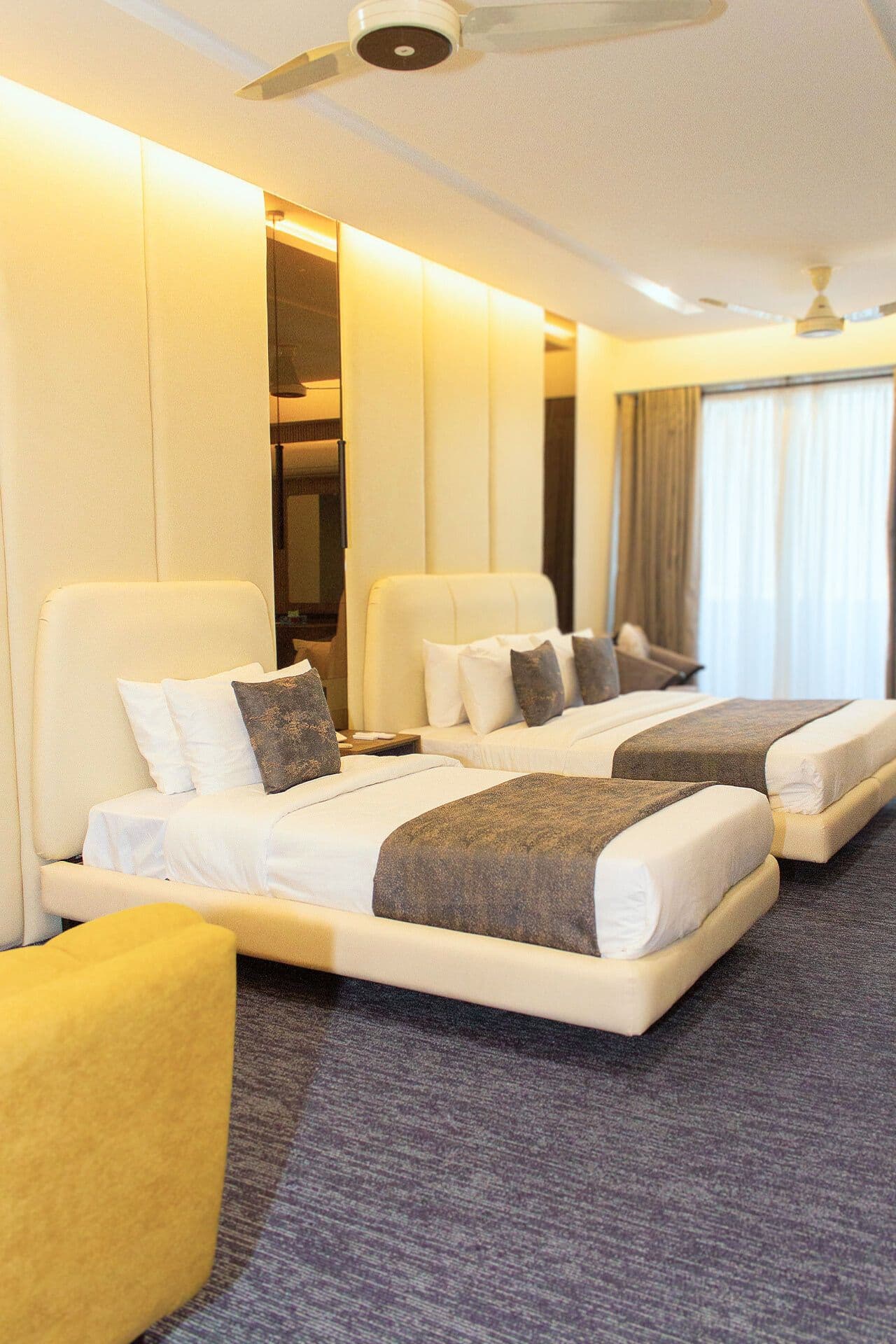 Family Room mobile view with king bed and single bed, curtains, window, study table, AC, mirrors, and pillows at LEORK Hotels Rawalpindi Islamabad