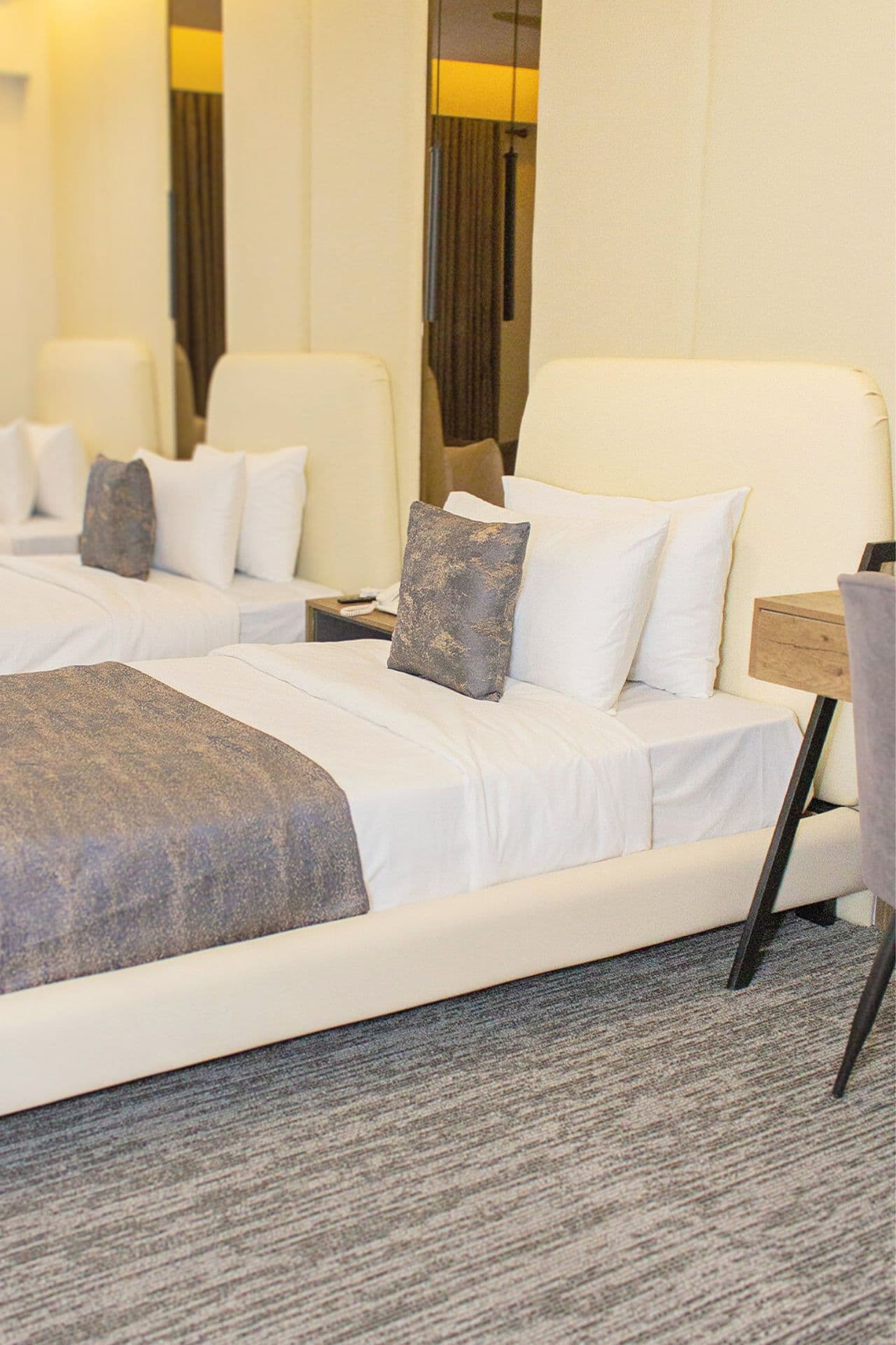 Triple Room mobile view with three single beds, study table, headboard, carpet, window, curtains, fridge, and wardrobe at LEORK Hotels Rawalpindi Islamabad