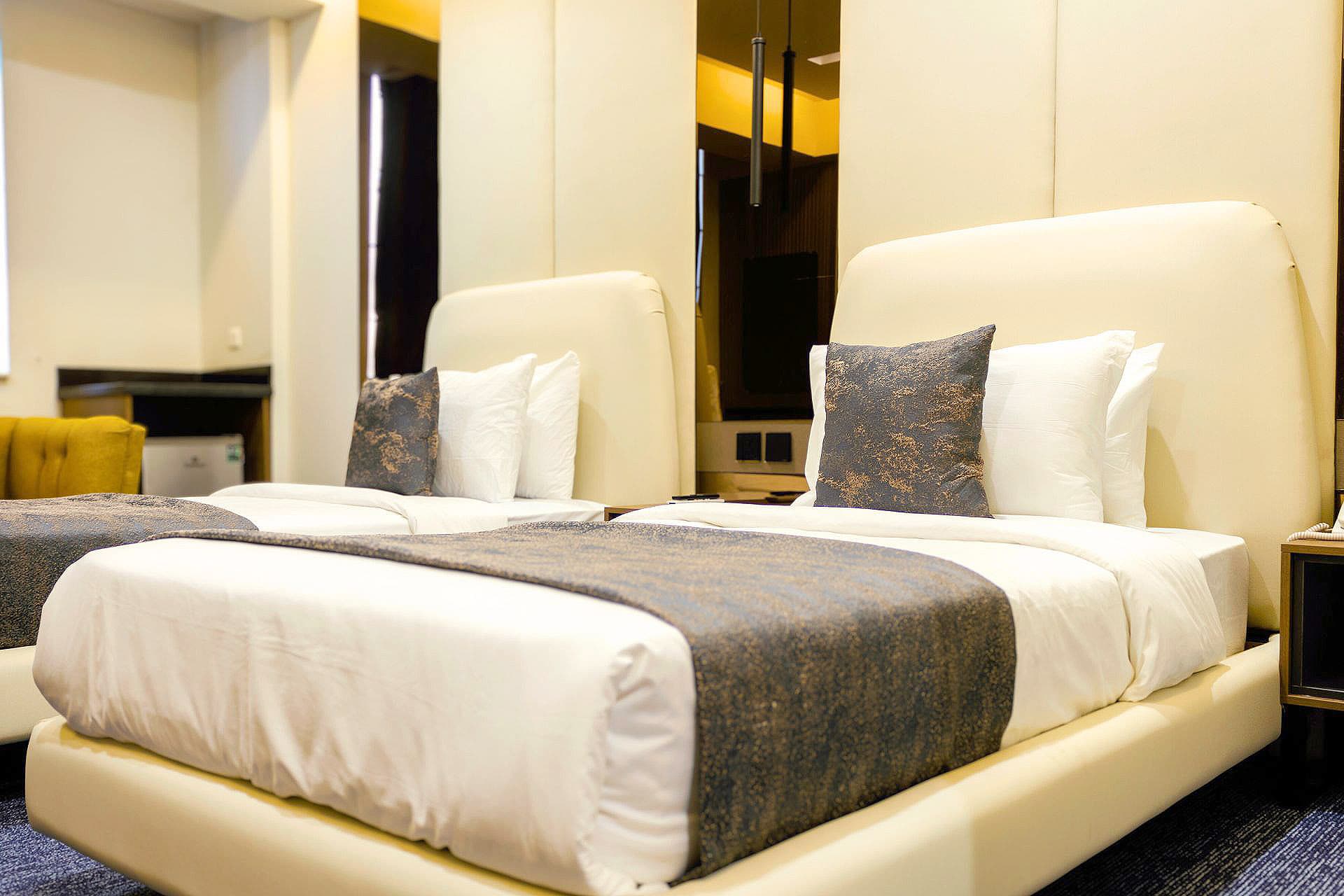 Twin Room full view with two single beds, headboards, pillows, mirror, lights, and carpet at LEORK Hotels Rawalpindi Islamabad