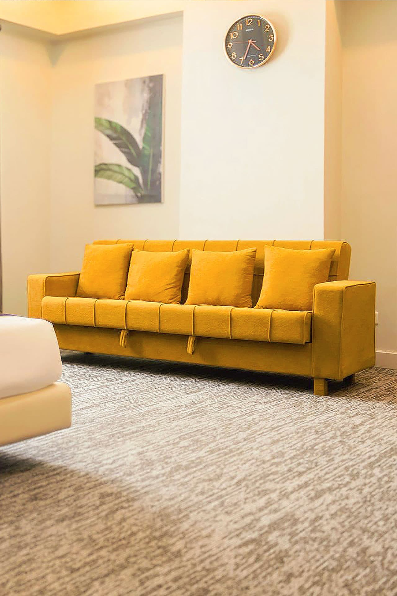 Twin Room mobile view with sofa cum bed, curtains, window, painting, carpet, and pillows at LEORK Hotels Rawalpindi Islamabad